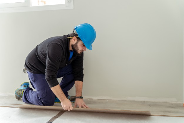 Man Carpenter Assembling Laminate Flooring. House Floor Renovation 
