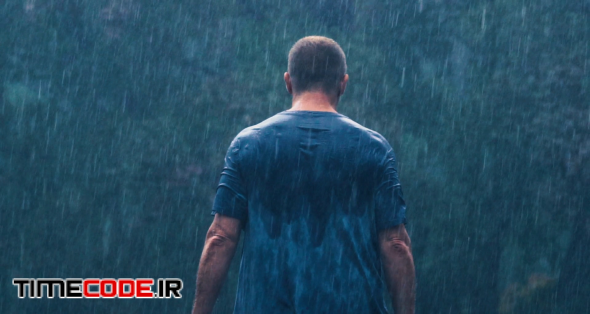 A soaked man walks away into a forest in a heavy rain and storm