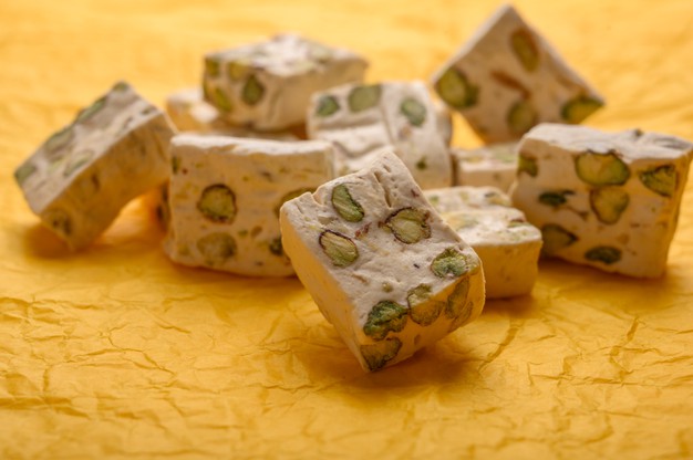 Eastern Arabic Nougat Sweetness With Pistachios On Yellow Paper Background. 