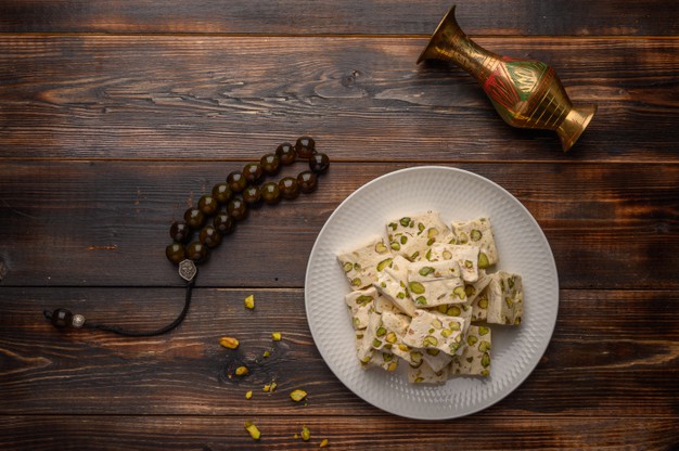Eastern Arabic Nougat Sweetness With Pistachios On A White Ceramic Plate On A Wooden Background. 