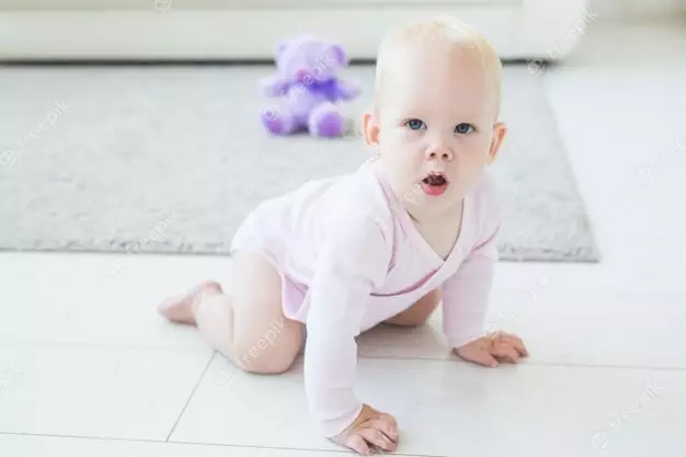 Portrait Of A Cute Baby Crawling And Laughing On The Floor At Home 