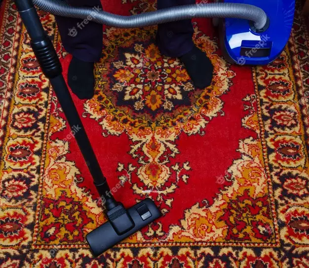 A Man Cleans An Old Carpet With An Electric Vacuum Cleaner 