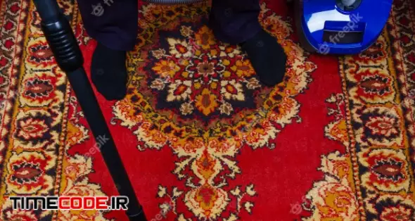 A Man Cleans An Old Carpet With An Electric Vacuum Cleaner 