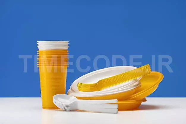 A Set Of Disposable Plastic Utensils. Yellow And White Plates, Glasses, Forks And Spoons. The Concep