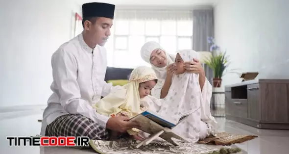 Portrait Of Happy Muslim Family With Children Reading Quran And Pray Together At Home