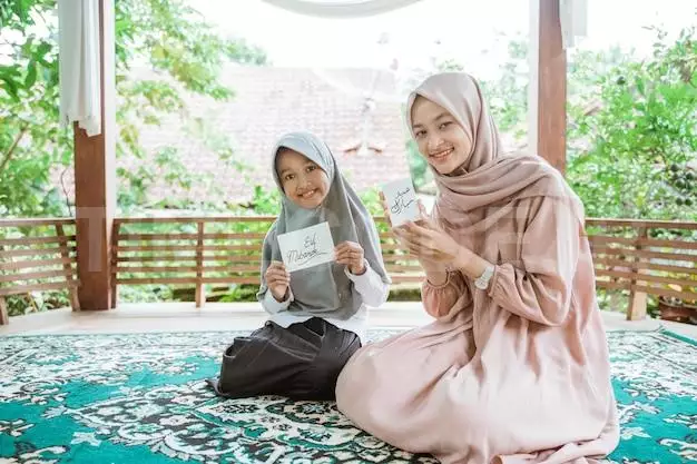 Veiled Asian Mother And Daughter Holding Eid Mubarak Greeting Cards