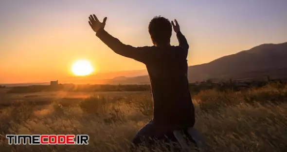 Man With Hands Raised In The Sunset