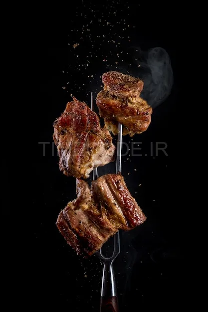 عکس گوشت سرخ شده روی چنگال در پس زمینه سیاه