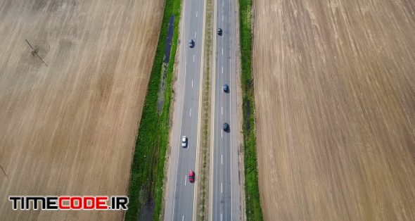 Aerial drone shot of empty motorway. Car driving through the road at the countryside, through the field.