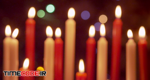 Red and white candles flickering and blown out in front of christmas decorations - soft focus - slow motion