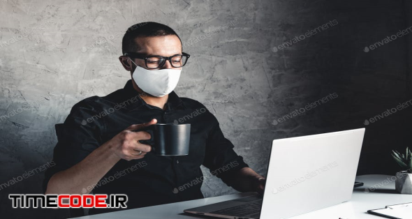 A Masked Man Works At A Computer. Pandemic, Coronavirus, Epidemic