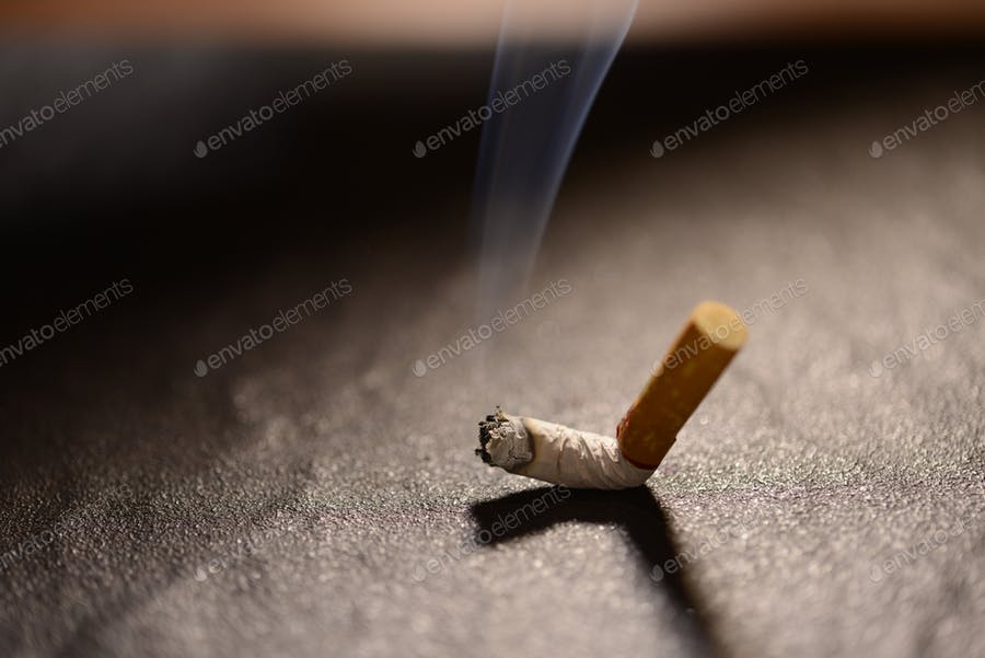 Lit Cigarette Butt With Smoke On The Ground