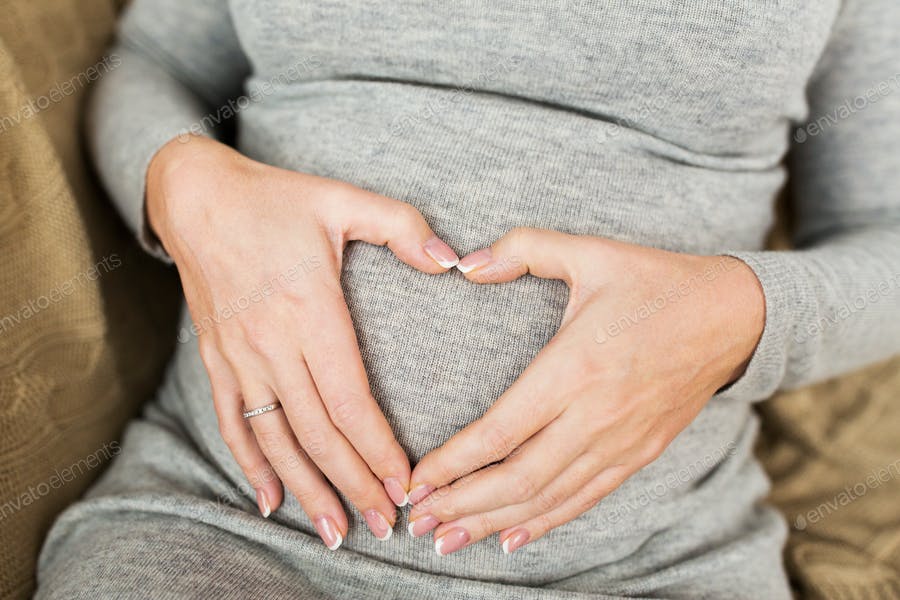 Pregnant Woman Making Heart Gesture On Her Belly