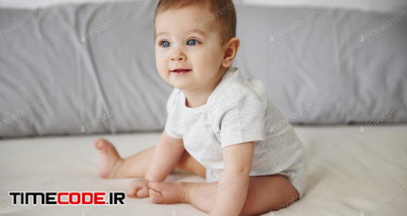 Adorable Baby Girl Sitting On Bed