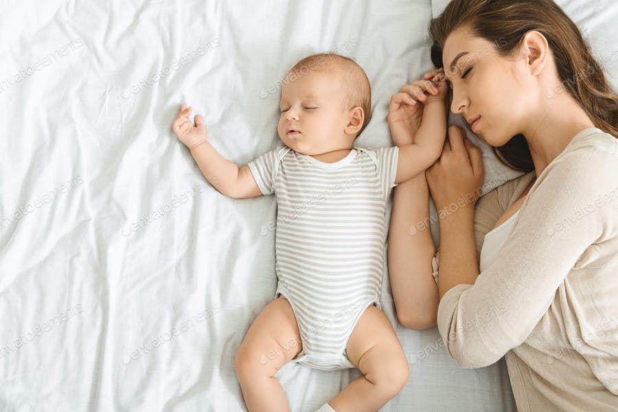 Young Mother And Cute Little Baby Co-sleeping Together In Bed