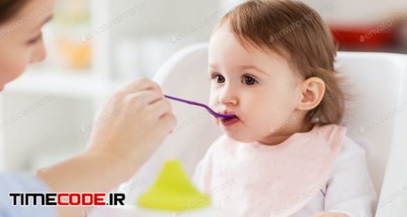 Happy Mother Feeding Baby With Puree At Home
