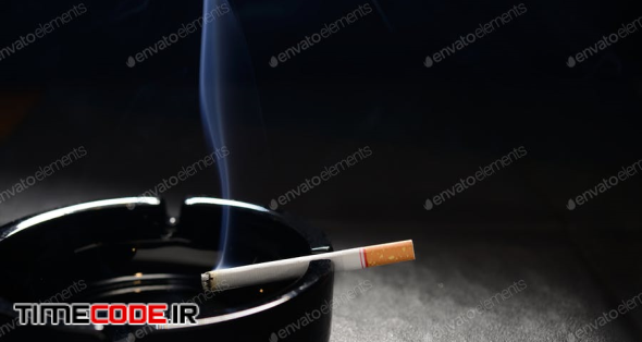 Lit Cigarette With Smoke Lying On An Empty Black Ashtray