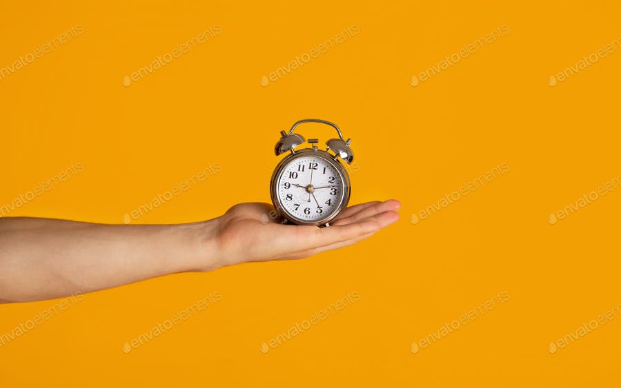 Time Management And Deadline. Millennial Guy Holding Alarm Clock Over Orange Background, Closeup