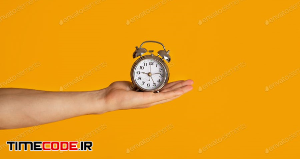 Time Management And Deadline. Millennial Guy Holding Alarm Clock Over Orange Background, Closeup