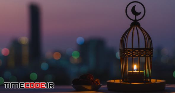 Lantern That Have Moon Symbol On Top And Small Plate Of Dates Fruit With Dusk Sky And City Bokeh Light Background For The Muslim Feast Of The Holy Month Of Ramadan Kareem. 